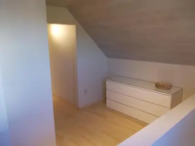 an attic room with a dresser and a light at Het Zolderhuis in Arendonk