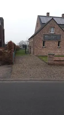a brick building with a sign on it next to a street at Het Zolderhuis in Arendonk