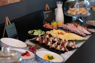 a buffet of food with meats and fruit on plates at Tulip Inn Antwerpen in Antwerp