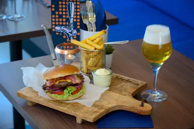 a wooden tray with a sandwich and a glass of beer at Tulip Inn Antwerpen in Antwerp