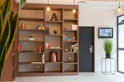 a book shelf in a room with bookshelves at Tulip Inn Antwerpen in Antwerp
