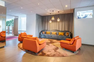a living room with orange chairs and a couch at Crowne Plaza Antwerpen by IHG in Antwerp
