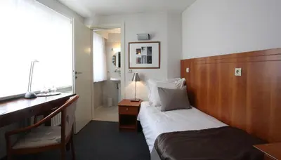 a bedroom with a bed with a wooden headboard and a desk at Theater Hotel Leuven Centrum in Leuven