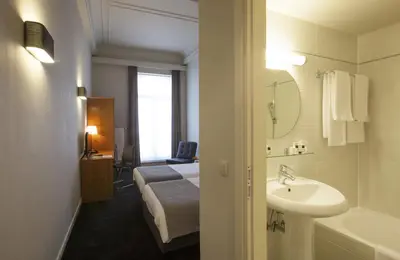a bathroom with a sink and a bed and a tub at Theater Hotel Leuven Centrum in Leuven