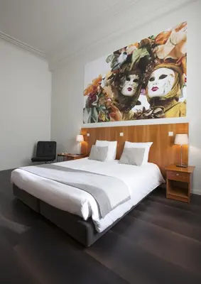 a bedroom with a large bed with a painting on the wall at Theater Hotel Leuven Centrum in Leuven