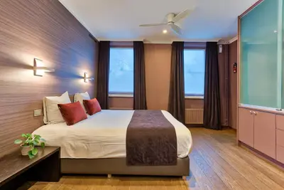 a bedroom with a large bed and two windows at Hotel Astoria Gent in Ghent