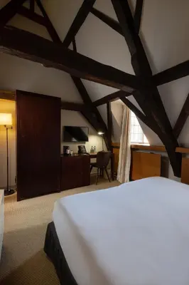 a bedroom with a white bed and a tv at Martin's Klooster in Leuven