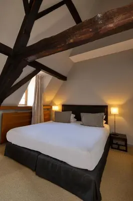 a bedroom with a large white bed in an attic at Martin's Klooster in Leuven
