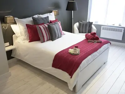 a bedroom with a large white bed with red and grey pillows at B&B Be In Brussels in Brussels