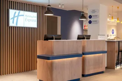 a lobby with a reception desk with a sign on the wall at Holiday Inn Express & Suites Ghent by IHG in Ghent
