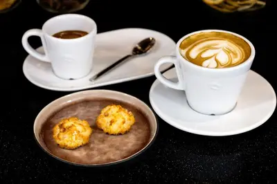 two cups of coffee and biscuits on a table at Courtyard by Marriott Brussels EU in Brussels