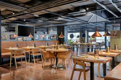 a restaurant with wooden tables and chairs and a flat screen tv at Courtyard by Marriott Brussels EU in Brussels