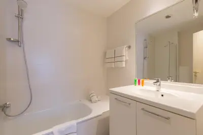 a white bathroom with a sink and a shower at Thon Hotel Residence Parnasse Aparthotel in Brussels