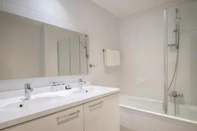a white bathroom with a sink and a shower at Thon Hotel Residence Parnasse Aparthotel in Brussels