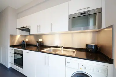 a white kitchen with a sink and a microwave at Thon Hotel Residence Parnasse Aparthotel in Brussels
