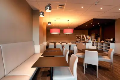 a restaurant with wooden tables and white chairs at Hotel Expo in Brussels