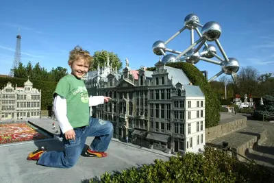 a young boy holding a skateboard in front of a statue at Hotel Expo in Brussels