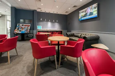 a waiting room with red chairs and tables and a tv at Hotel Expo in Brussels