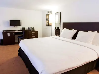 a large white bed in a hotel room with a desk at Hotel des Colonies Brussels by Mercure in Brussels