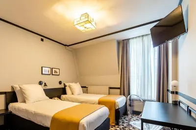 a hotel room with two beds and a table at Hotel des Colonies Brussels by Mercure in Brussels