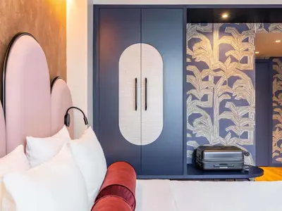 a bedroom with a bed and a cabinet at Hotel des Colonies Brussels by Mercure in Brussels