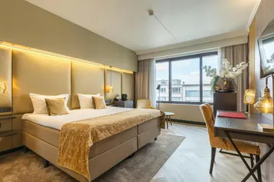 a hotel room with a bed and a desk at Leonardo Hotel Antwerp The Plaza in Antwerp
