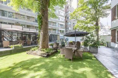 a garden with a table and chairs and an umbrella at Leonardo Hotel Antwerp The Plaza in Antwerp