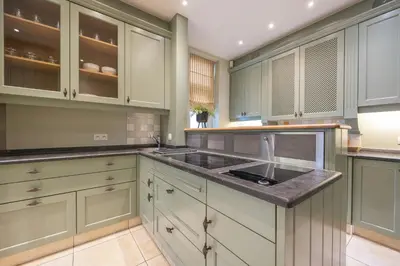 a kitchen with green cabinets and a sink at Leonardo Hotel Antwerp The Plaza in Antwerp