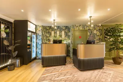 a lobby with a waiting area with trees and plants at Leonardo Hotel Antwerp The Plaza in Antwerp
