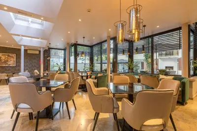 a restaurant with tables and chairs and windows at Leonardo Hotel Antwerp The Plaza in Antwerp