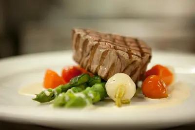 a plate of food with a piece of steak and vegetables at Hotel Le Châtelain in Brussels