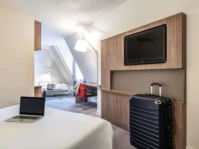 a hotel room with a bed with a laptop and a tv at Hotel Novotel Brussels Off Grand Place in Brussels