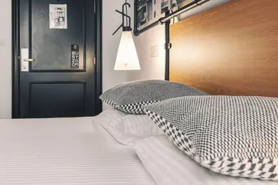 a bed with a wooden headboard and two pillows on it at Zoom Hotel in Brussels