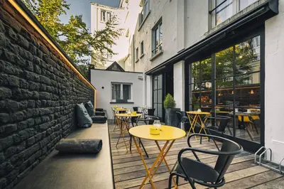 a patio with tables and chairs next to a brick wall at Zoom Hotel in Brussels