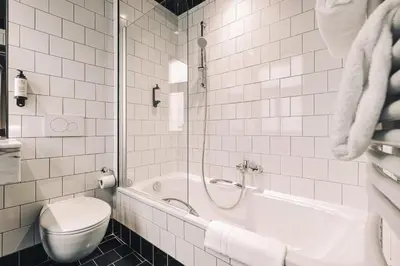 a white bathroom with a toilet and a bath tub at Zoom Hotel in Brussels
