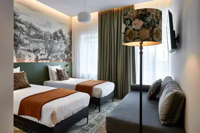 a hotel room with two beds and a couch at Urban Yard Hotel in Brussels