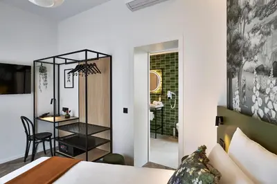 a bedroom with a bed and a table and a bathroom at Urban Yard Hotel in Brussels