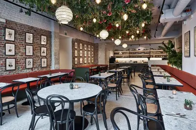 a dining room with tables and chairs and chandeliers at Urban Yard Hotel in Brussels