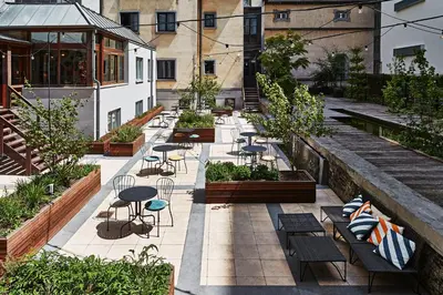 a courtyard with benches and tables and plants at Urban Yard Hotel in Brussels