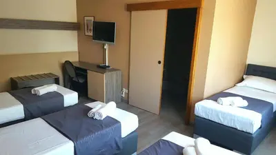 a hotel room with three beds and a tv at Hotel Prince de Liege in Brussels