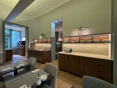 a dining room with tables and chairs and a kitchen at Hotel Du Congres in Brussels