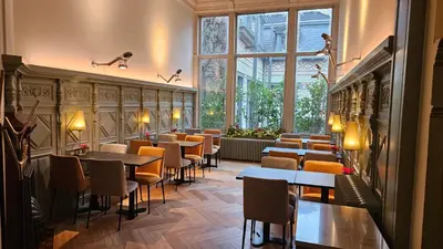 a restaurant with tables and chairs and a large window at Hotel Du Congres in Brussels