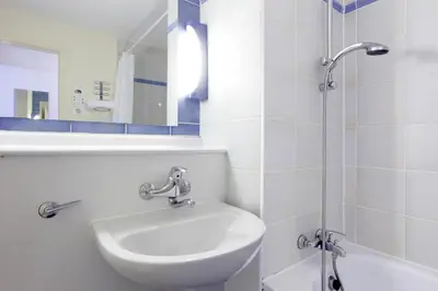 a white bathroom with a sink and a shower at Campanile Hotel & Restaurant Gent in Ghent
