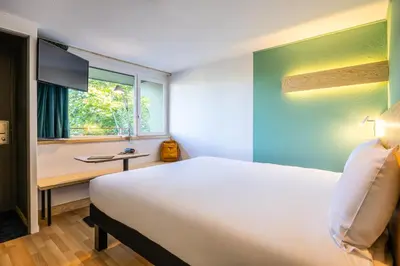a bedroom with a bed and a desk and a window at greet Brussels Airport Zaventem in Zaventem