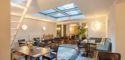 a restaurant with tables and chairs and a skylight at Hotel The Shepherd in Leuven