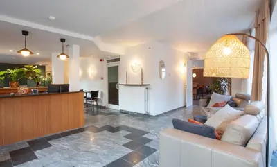 a living room with a white couch and a kitchen at Hotel The Shepherd in Leuven