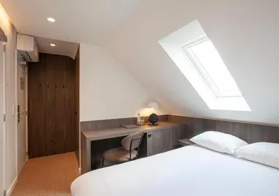 a bedroom with a bed and a desk and a skylight at Hotel The Shepherd in Leuven
