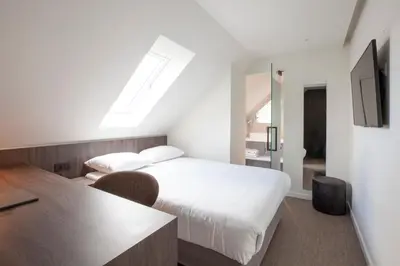 a bedroom with a bed and a desk and a tv at Hotel The Shepherd in Leuven