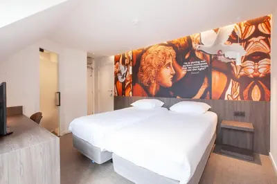 a bedroom with two beds and a large painting on the wall at Hotel The Shepherd in Leuven
