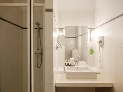 a white bathroom with a sink and a shower at Ghent River Hotel in Ghent